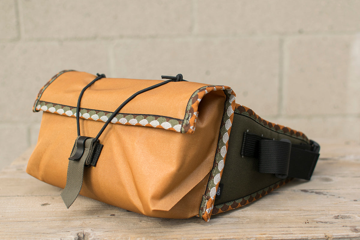 Side view of grey Little Dumpling hip pack with Great Horned Owl trim tape and top unrolled.