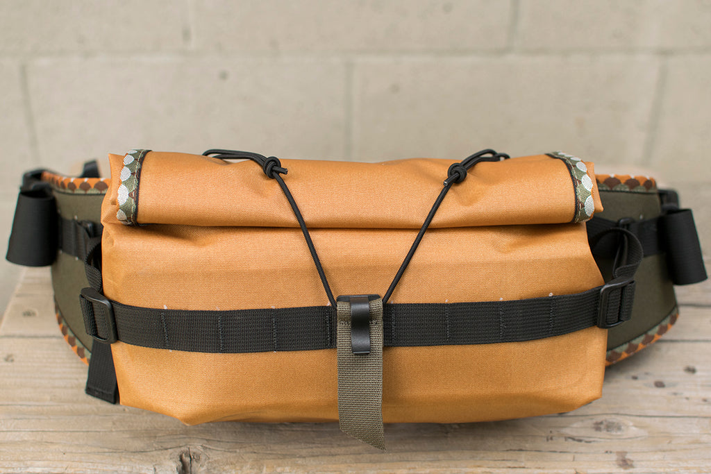 A front view of the orange Big Dumpling hip pack with Brown Trout patterned trim tape.