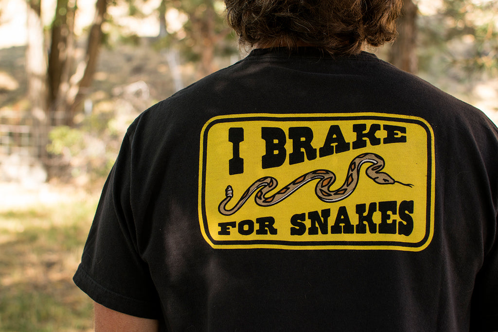 Person wearing a black t-shirt with 'I Brake for Snakes' graphic on the back.