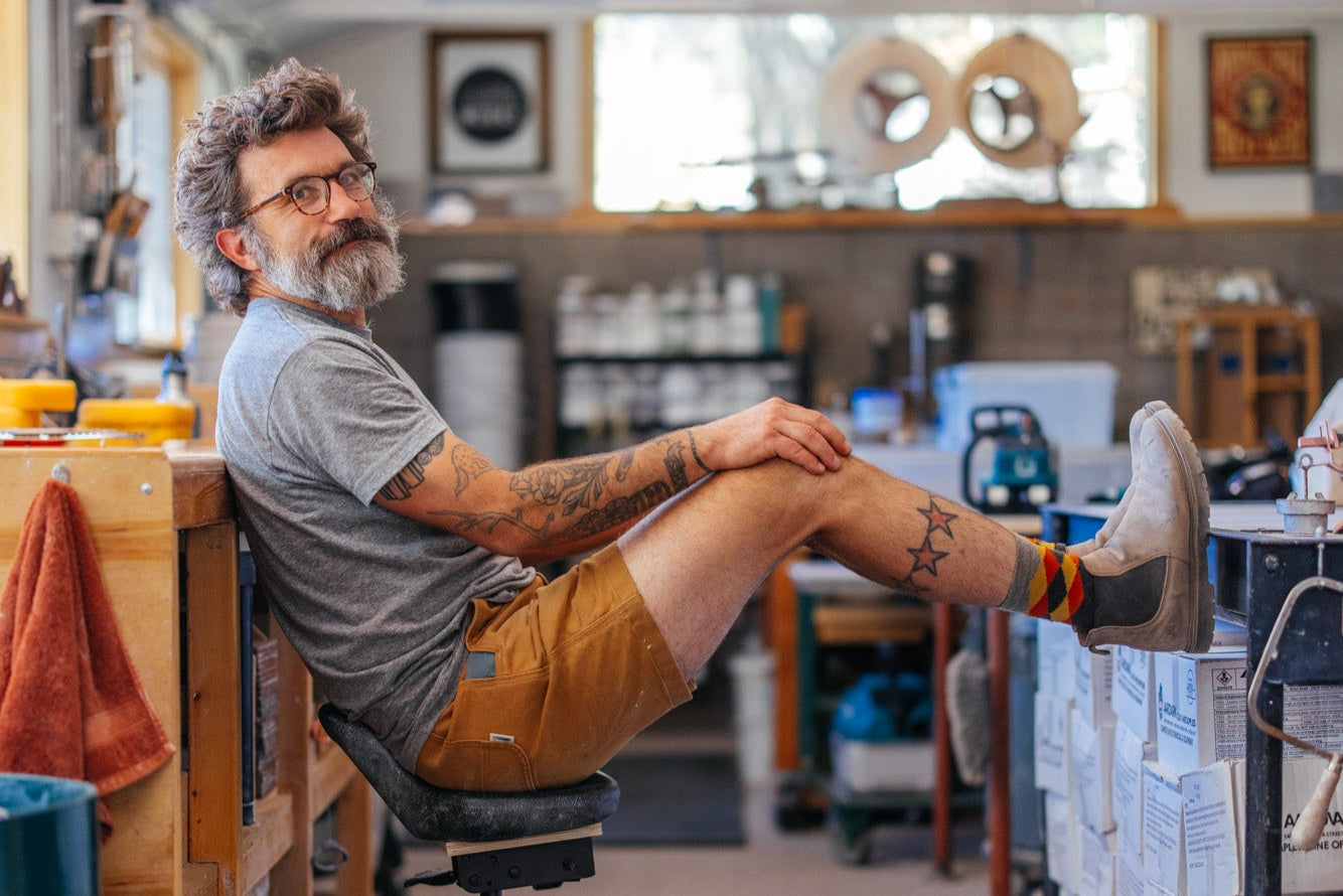Man sitting on a chair with his feet up in a pottery shop.