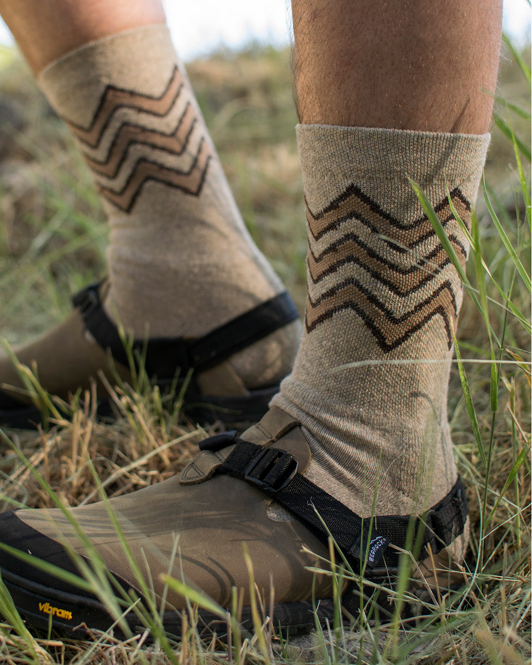 Person wearing Great Horned Owl socks and Mountain Clogs in grassy area