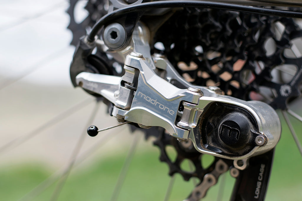 Black cable cherry on the shift cable of a machined Madrone rear derailleur.