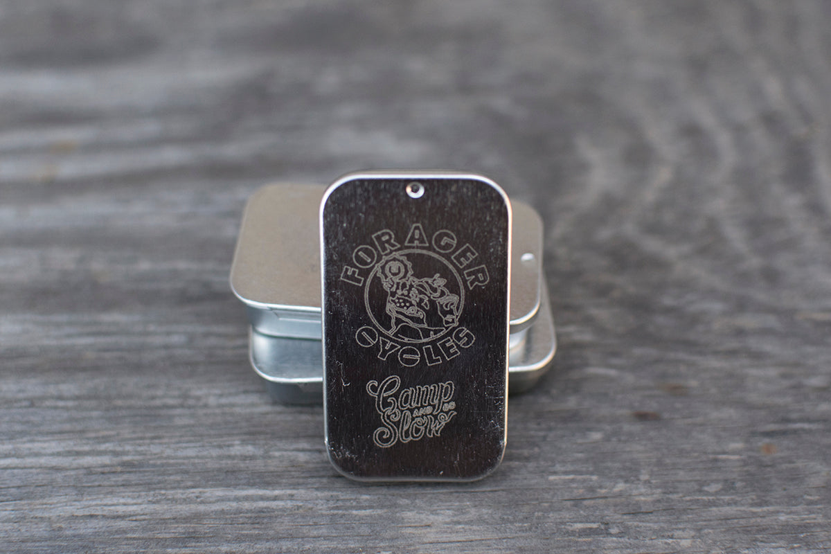 Tin lid engraved with the Forager Cycles and Camp And Go Slow logos.